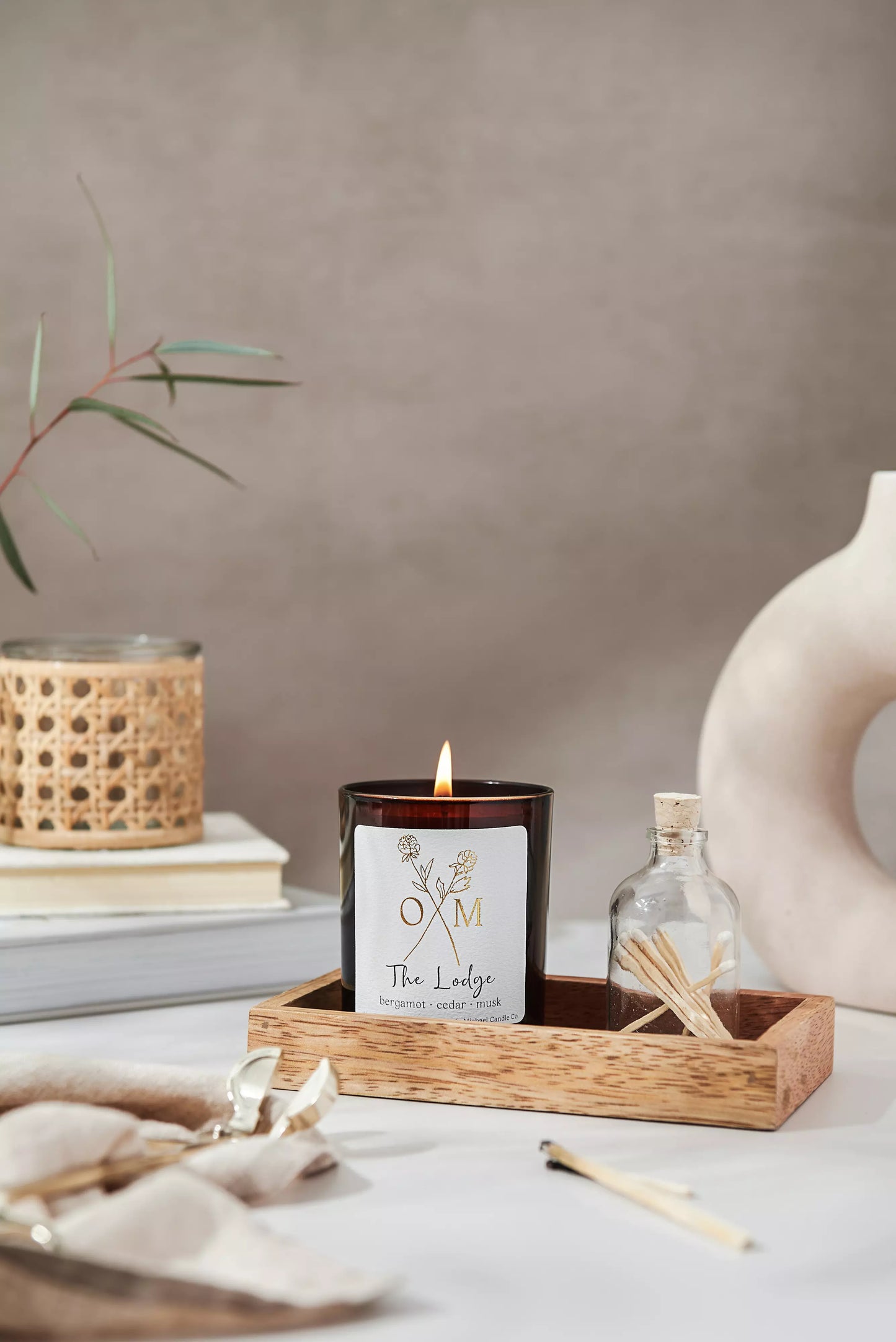 Our The Lodge scented candle is lit and on display in an amber glass jar.