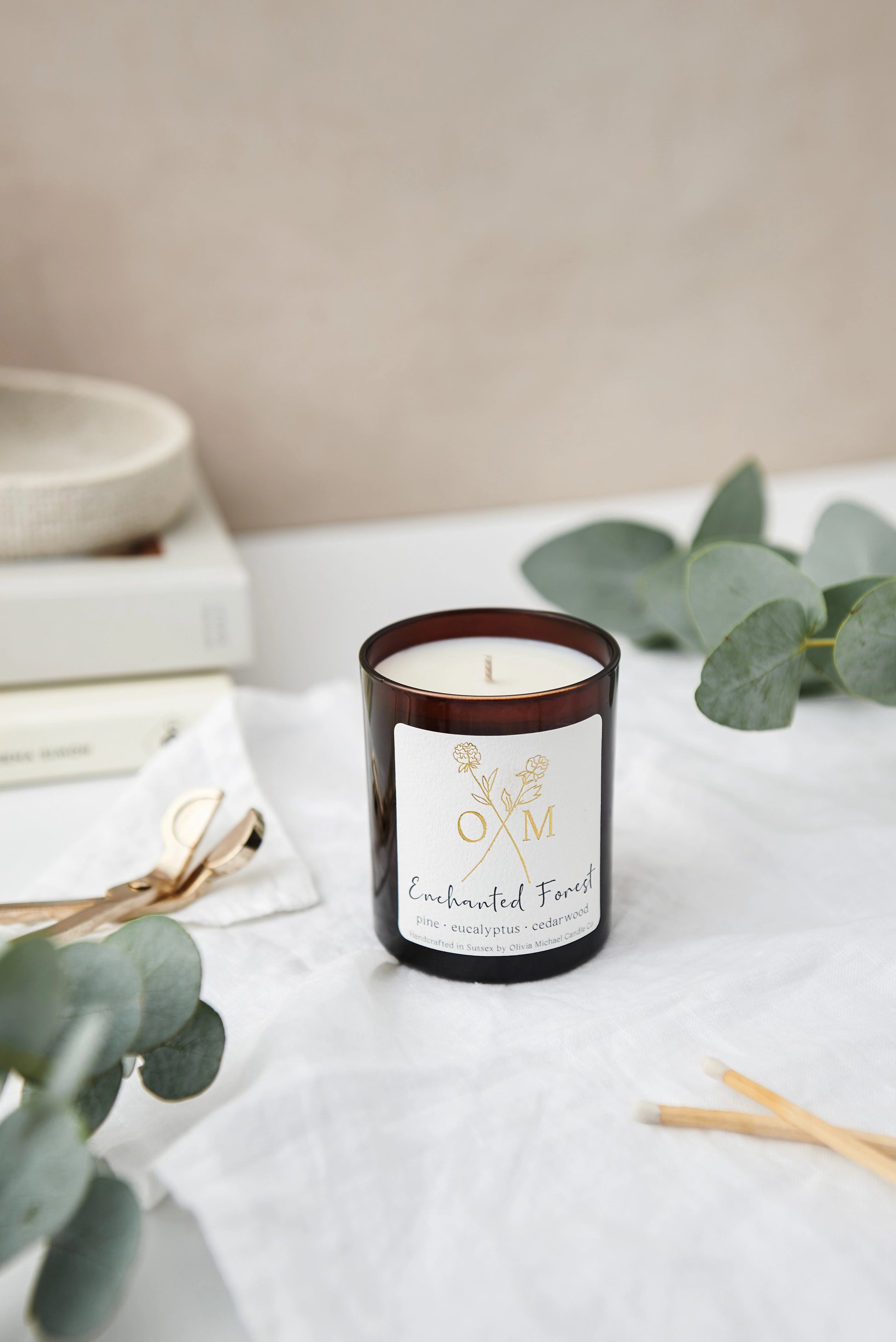Our Enchanted Forest scented candle is lit and on display in an amber glass jar.