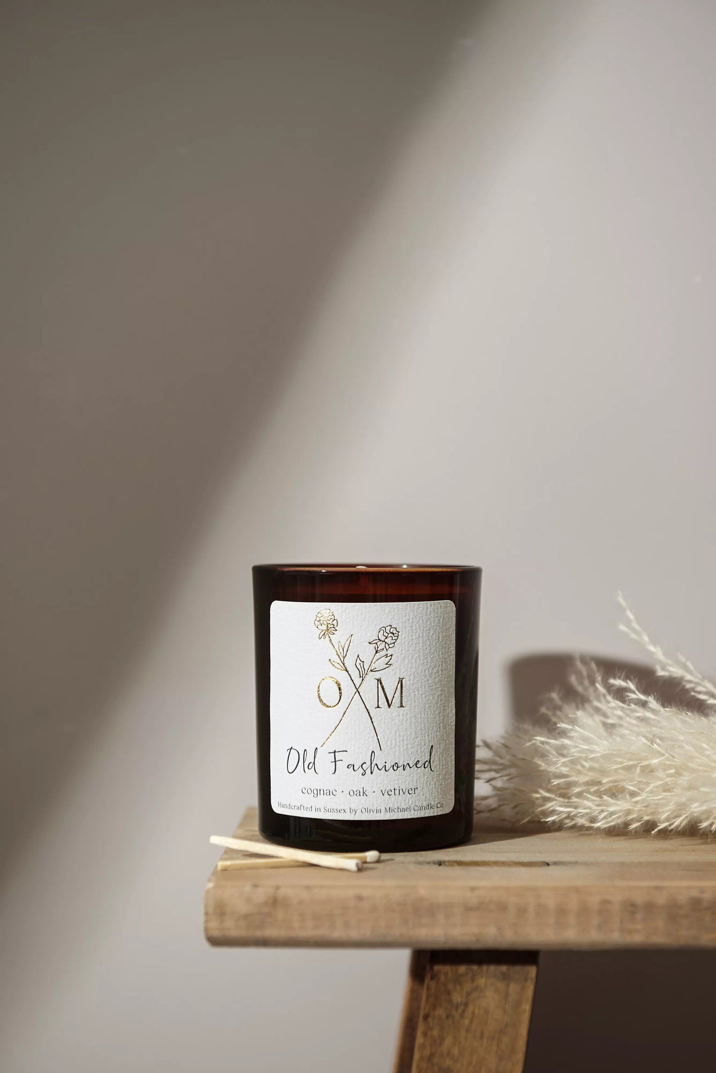 Our oak and vetiver scented candle is on display in an amber glass jar.