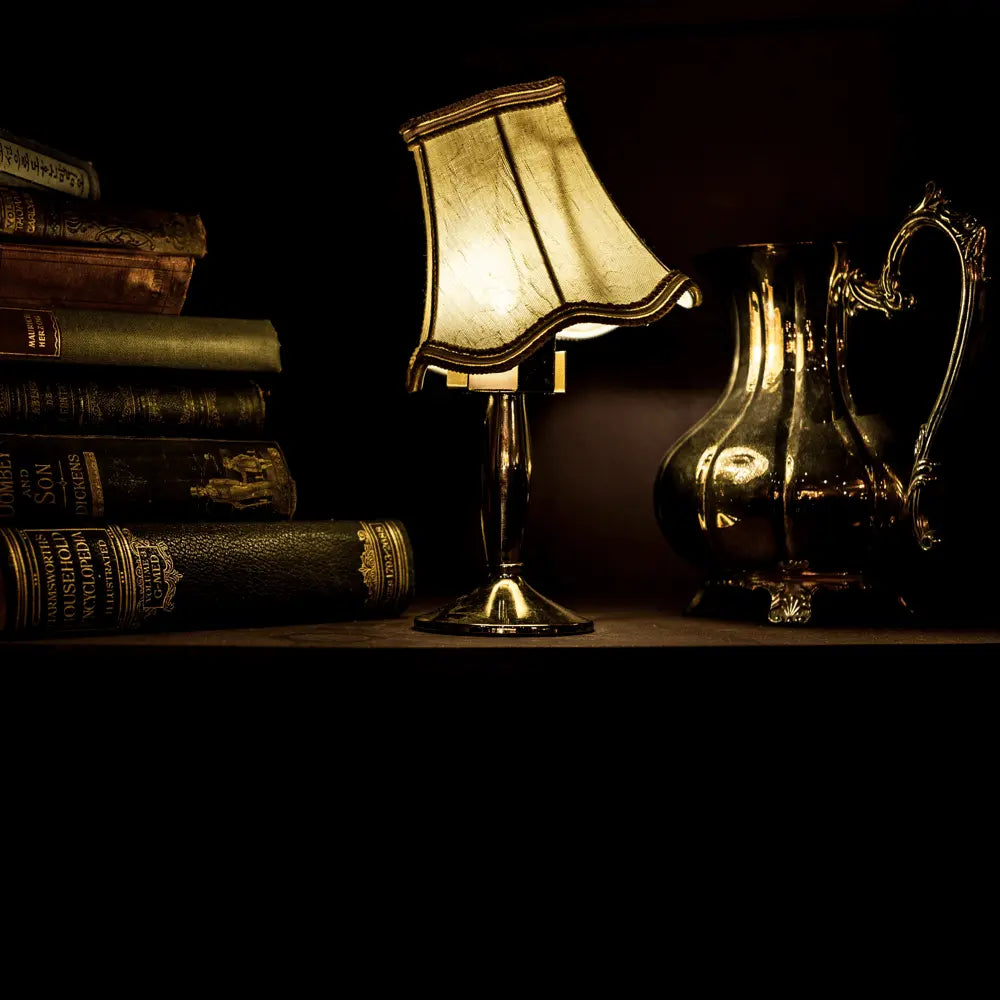 A dark image of a stack of books, lit with an old lamp.