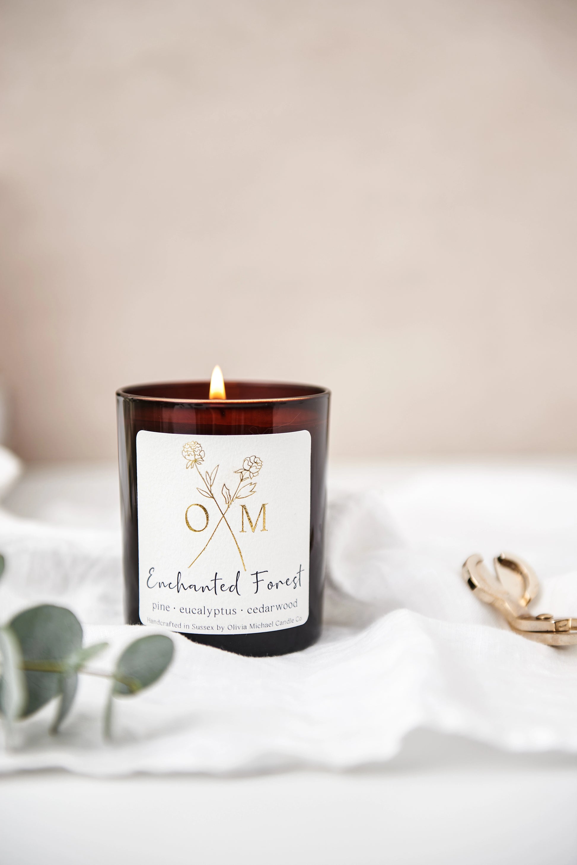 Our pine and eucalyptus scented candle is on display in an amber glass jar.