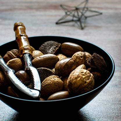 A bowl of Christmas nuts with a nutcracker resting on top.