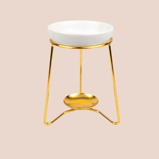 Gold metal tea light wax melt burner with a white ceramic dish on top.