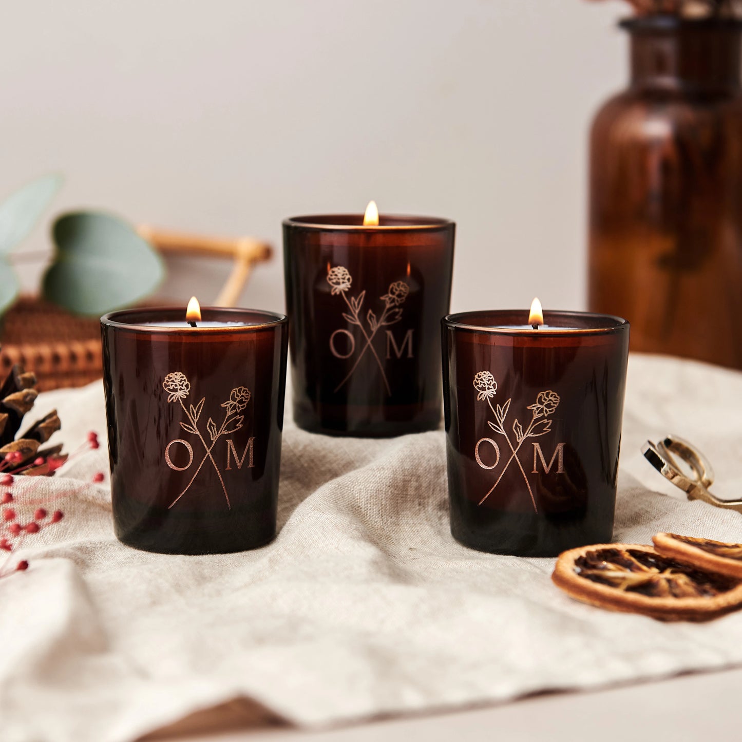 A trio of candles from our Winter Collection candle giftset. The candlelight brightens up the etched logo in the glass.