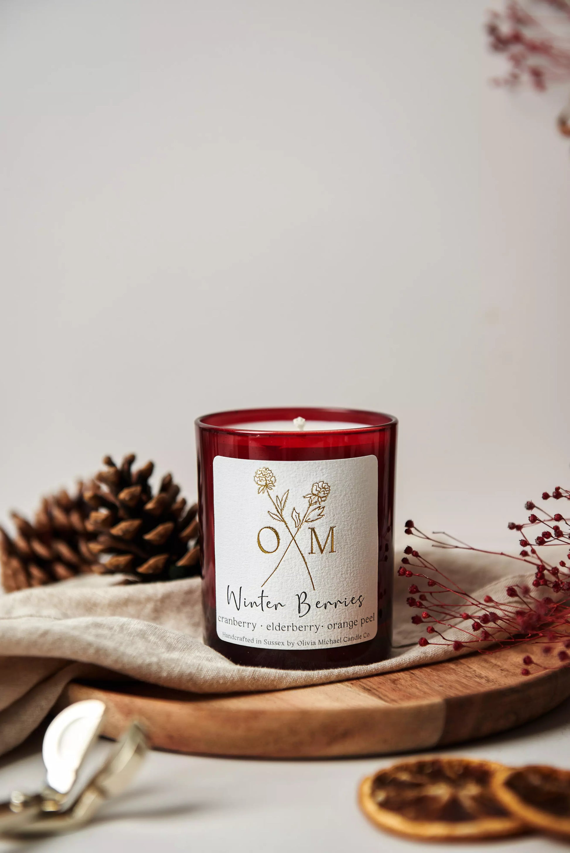 Our cranberry and elderberry scented candle is on display in an amber glass jar.