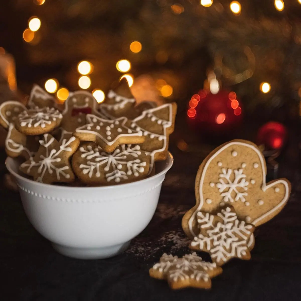 A white bowl of homemade gingerbread against the background of a blurred Christmas tree with lights