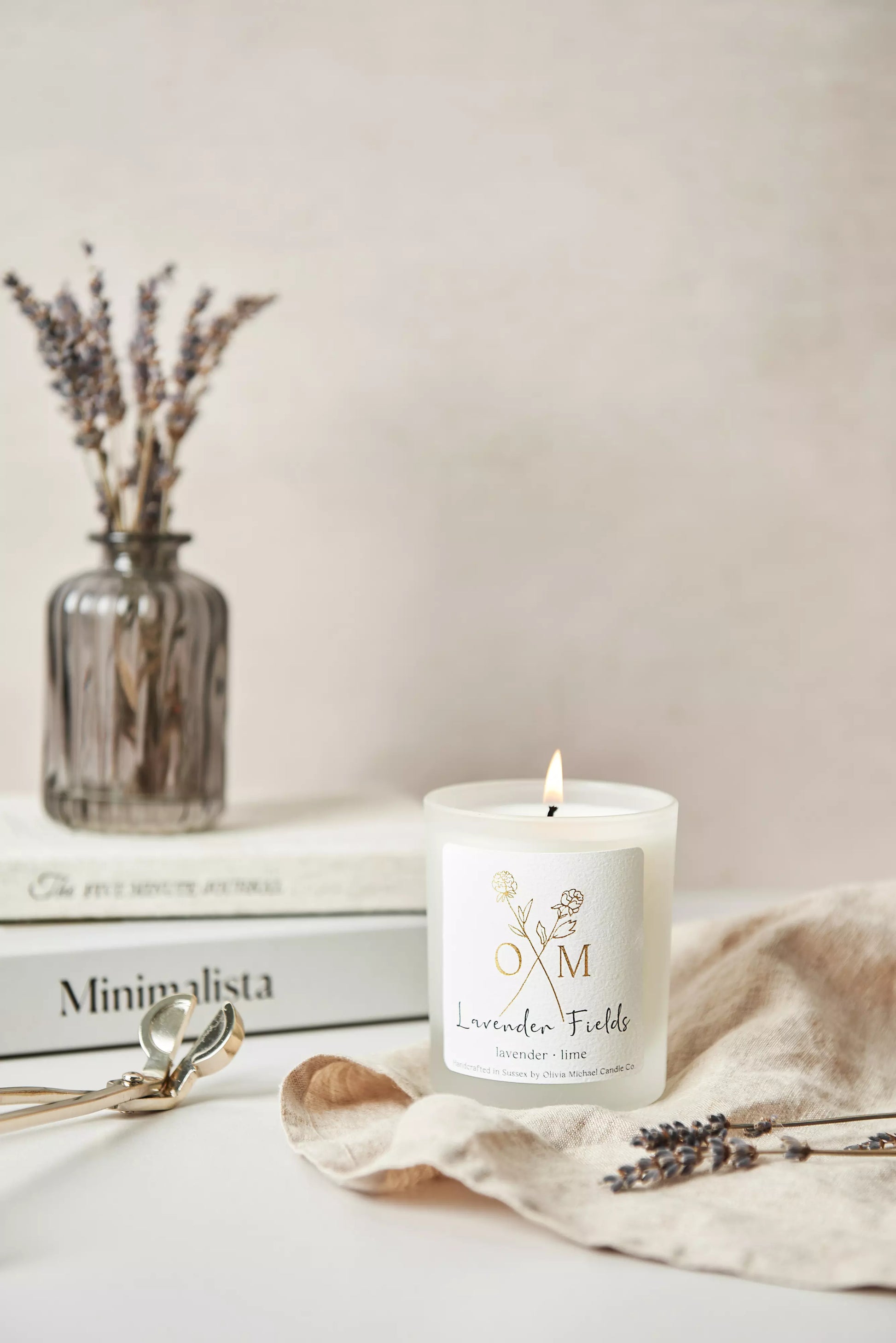 Our lavender aromatherapy candle is lit and on display in a clear frosted glass jar.