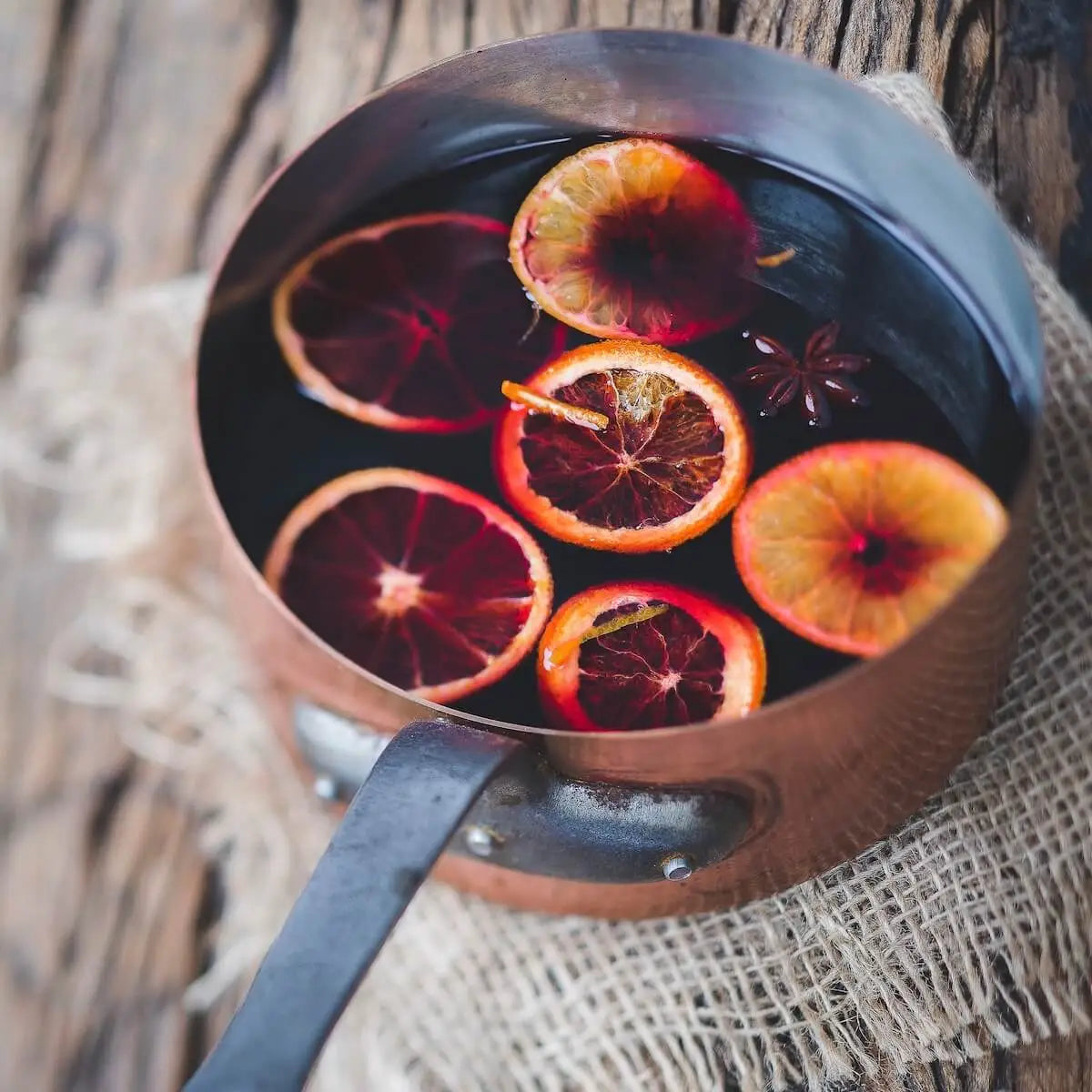 Mulled wine, orange slices and spices in a copper saucepan