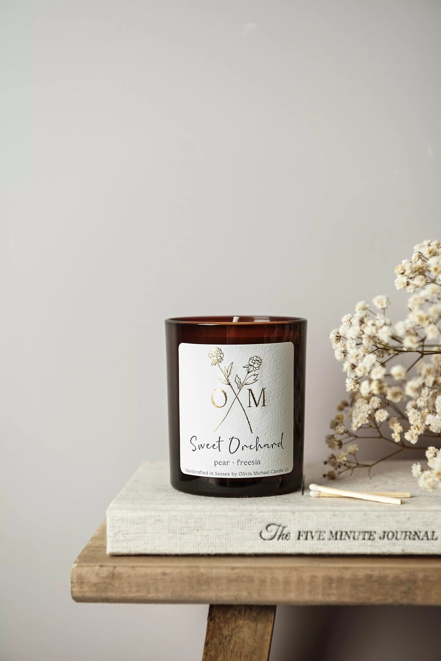 Our pear and freesia scented candle is on display in an amber glass jar.