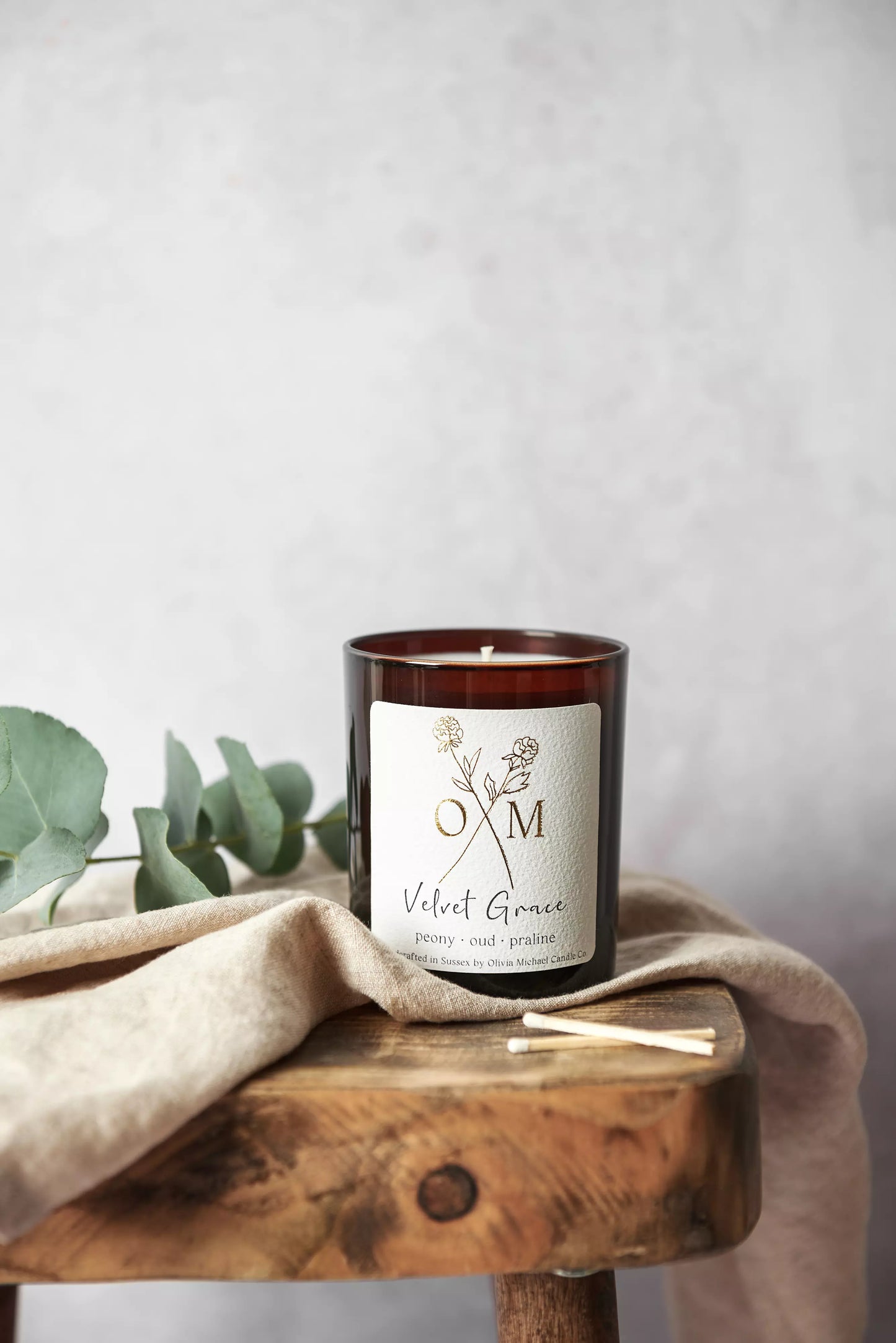 Our peony and oud scented candle is on display in an amber glass jar.