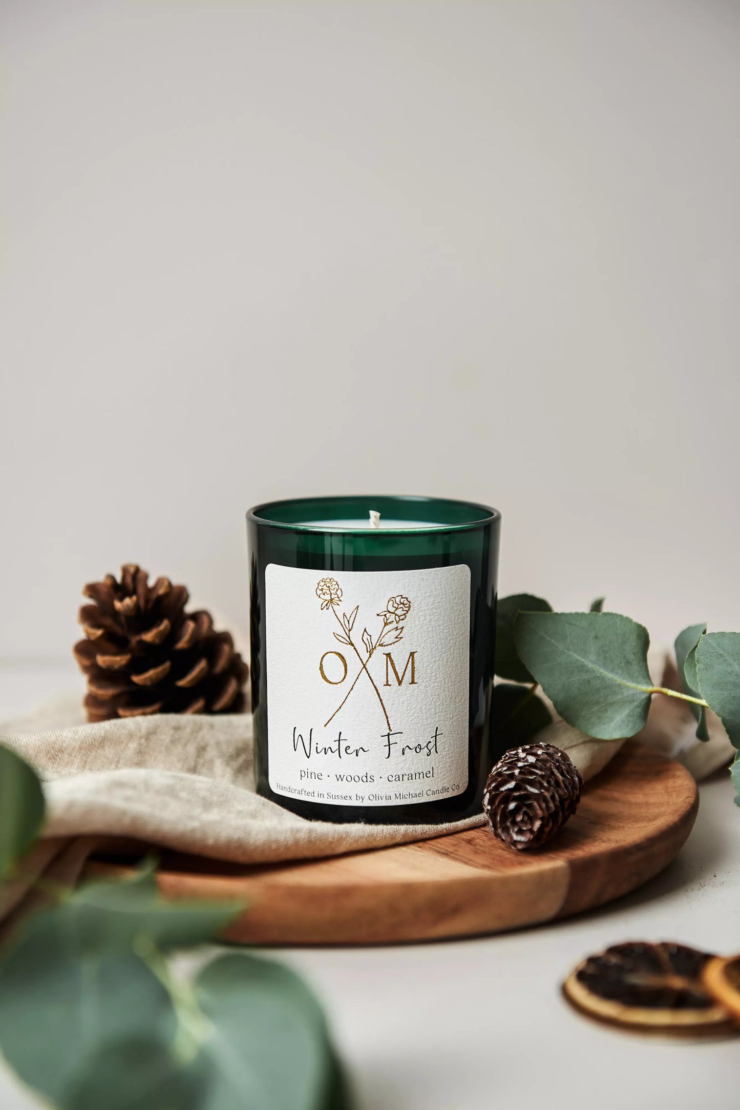 Our pine and caramel scented candle is on display in an amber glass jar.