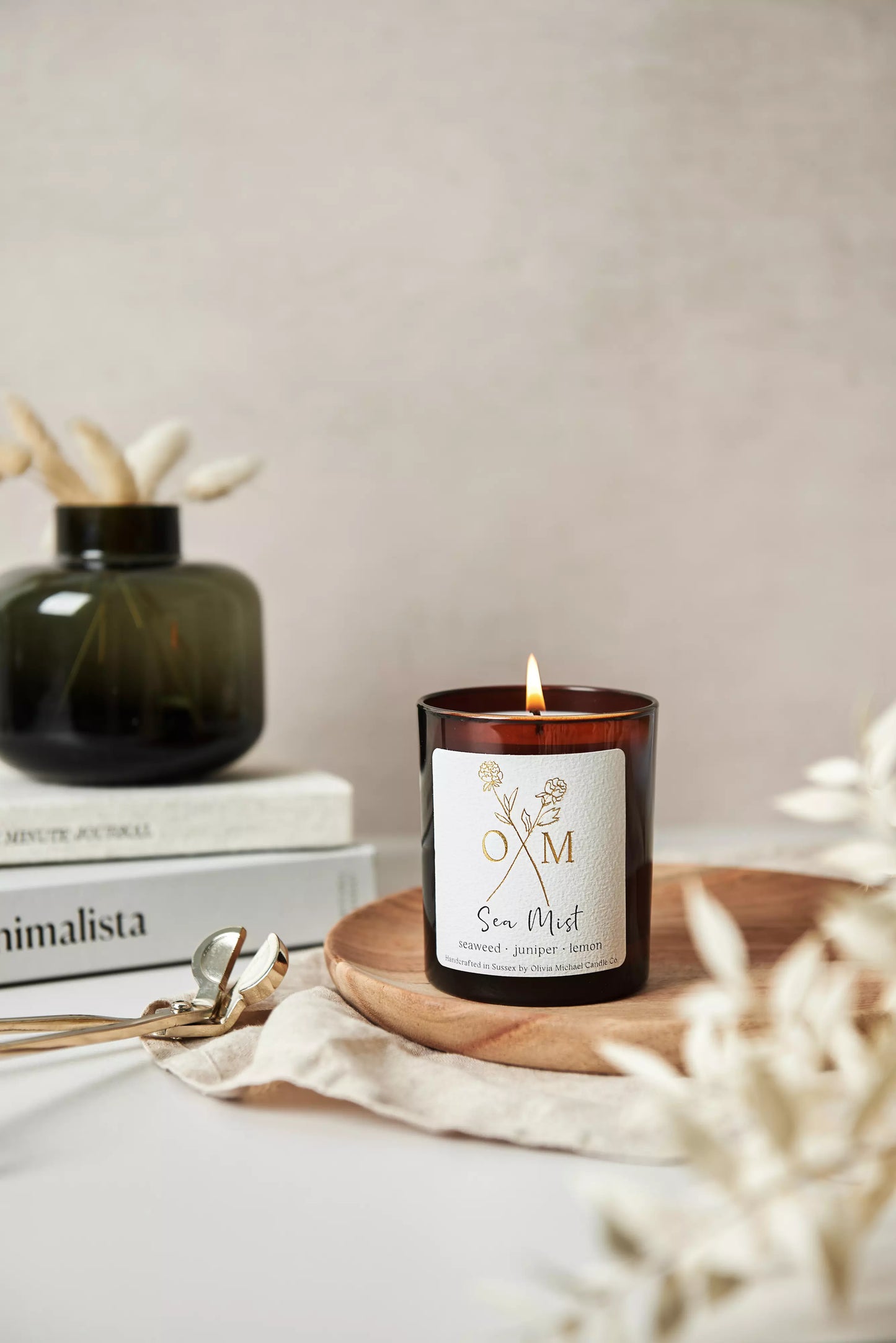Our seaweed and juniper scented candle is lit and on display in an amber glass jar.
