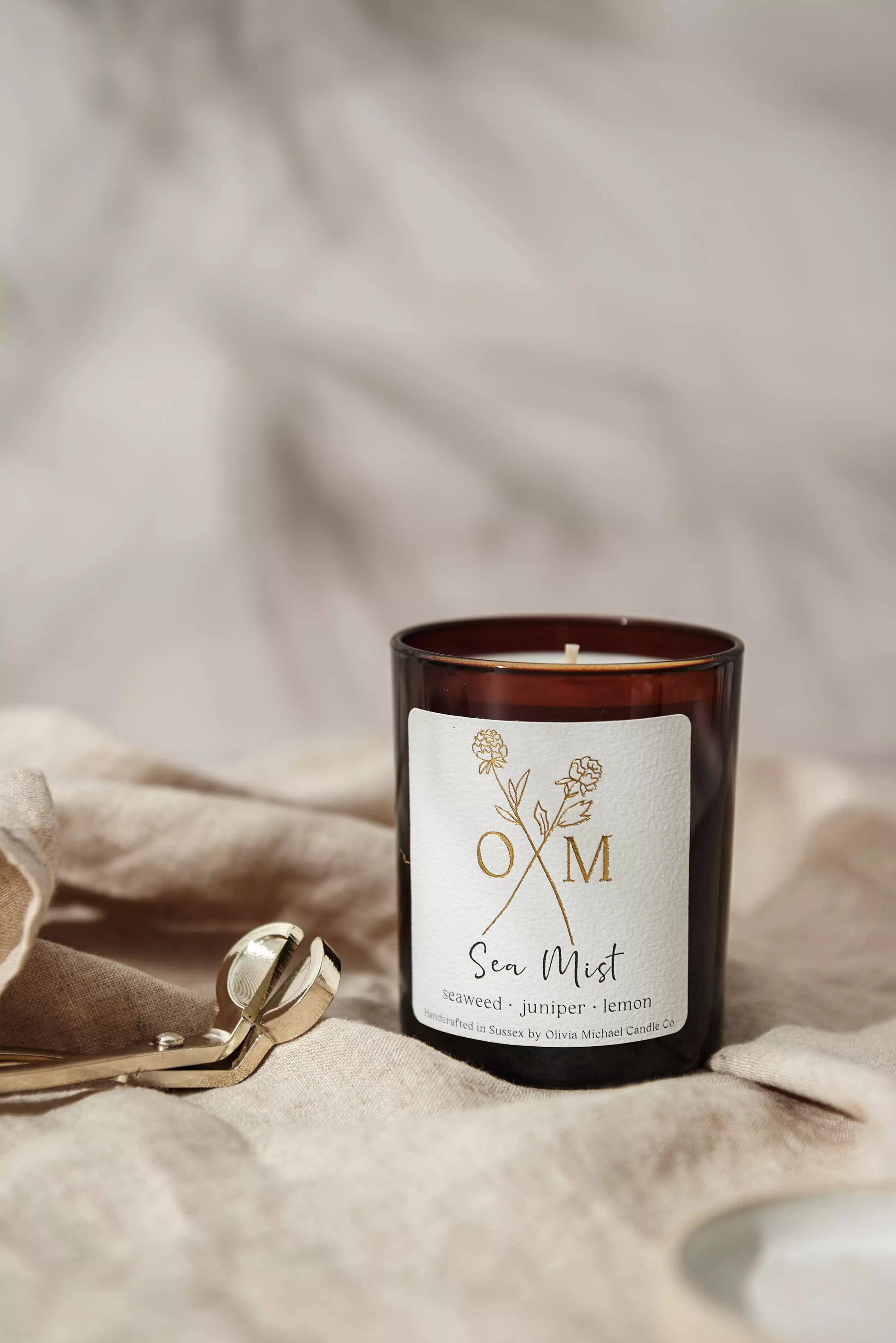 Our seaweed and juniper scented candle is on display in an amber glass jar.