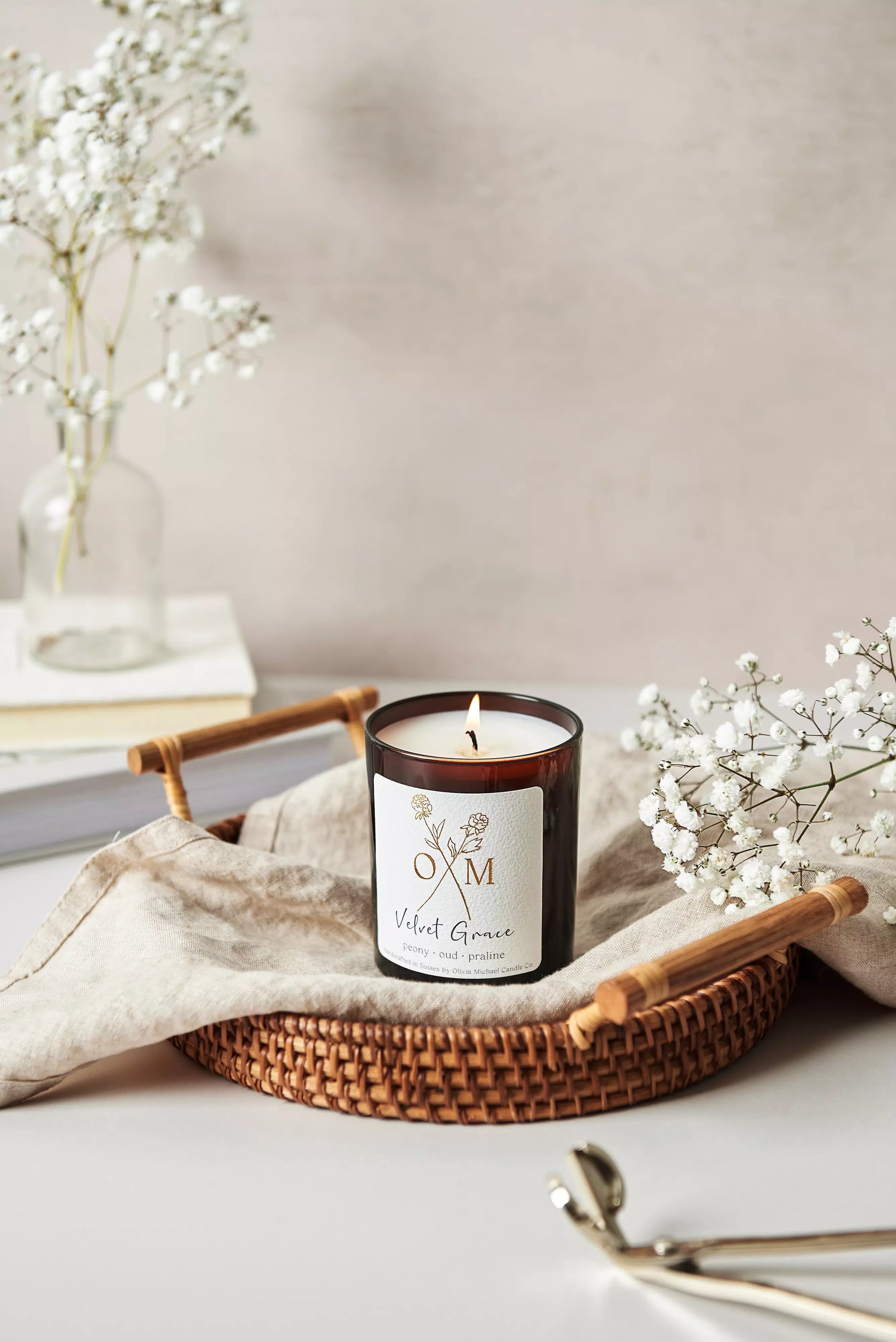 Our peony and oud scented candle is lit and on display in an amber glass jar.