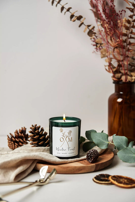 Our pine and caramel scented candle is lit and on display in an amber glass jar.